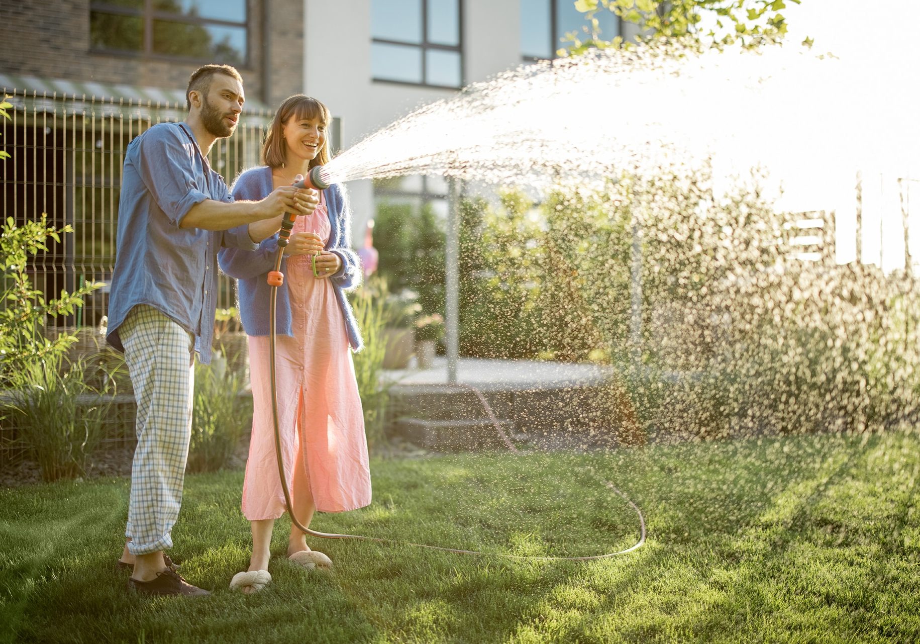 lovely-couple-watering-lawn-at-backyard-2023-11-27-05-08-29-utc
